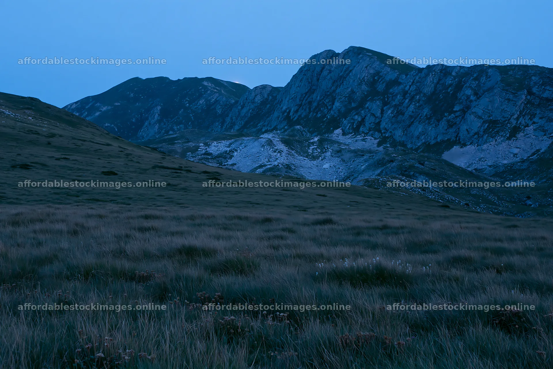 Moonrise over a meadow and mountains in twilight – stock images 9722x6480