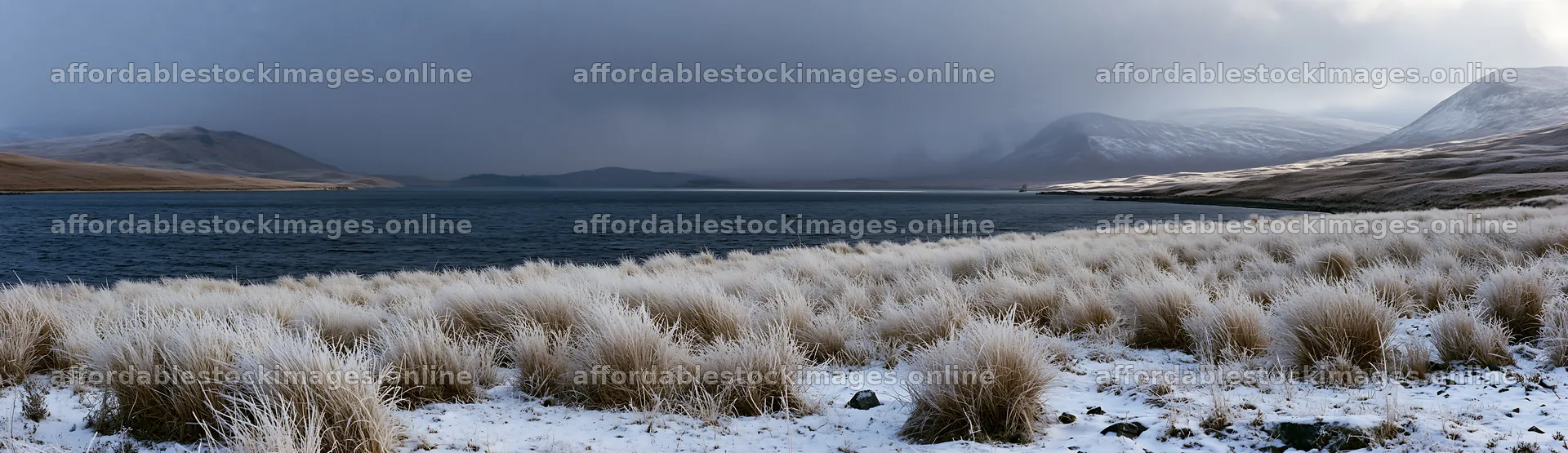 Snowy lakeside meadow with grass and distant mountains – stock images 14762x4268