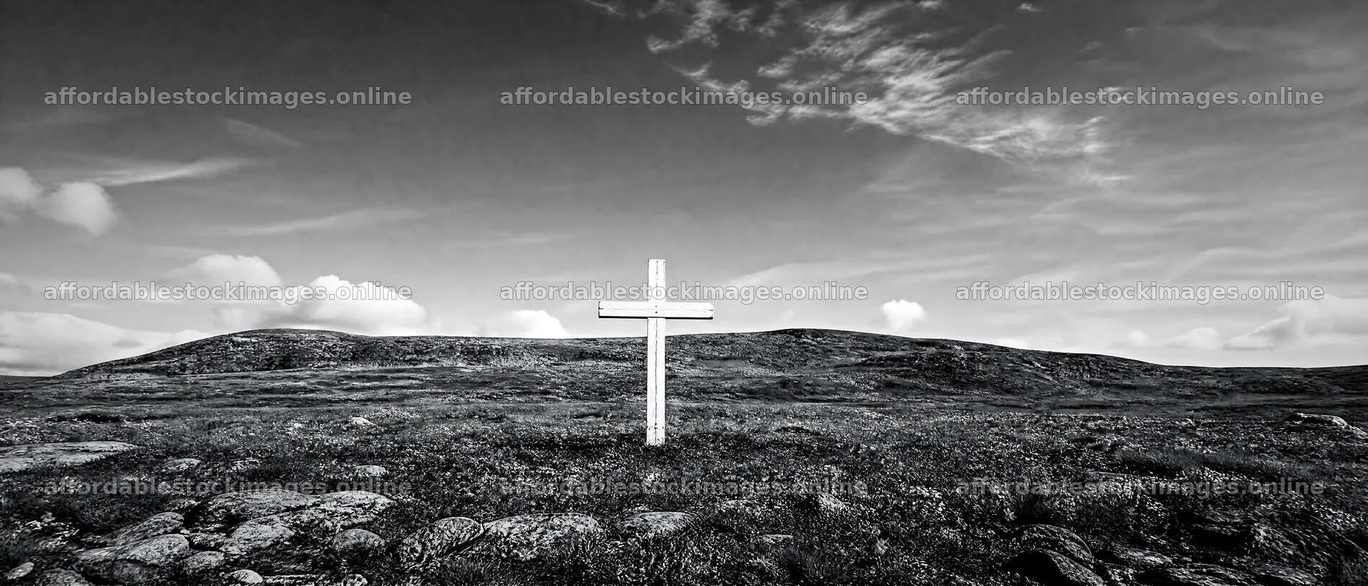 White Christian cross in wildflower meadow under cloudy sky – stock images 12124x5196